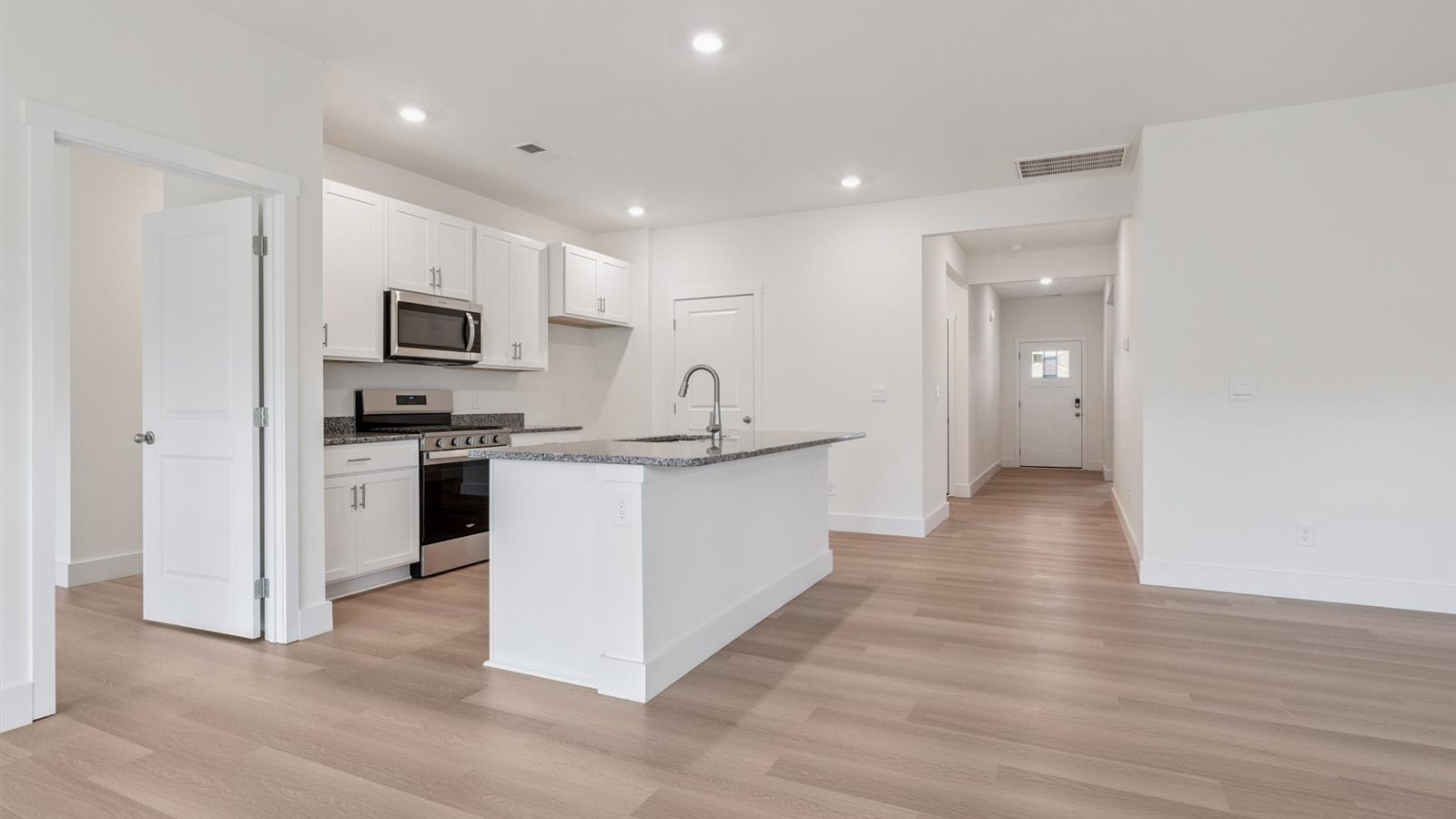 Open concept kitchen with stainless steel appliances, shaker style cabinets, and elevated finishes
