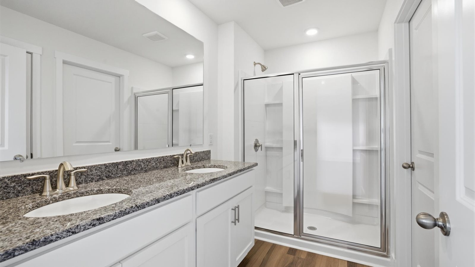 primary bathroom with double granite topped vanity and walk in shower