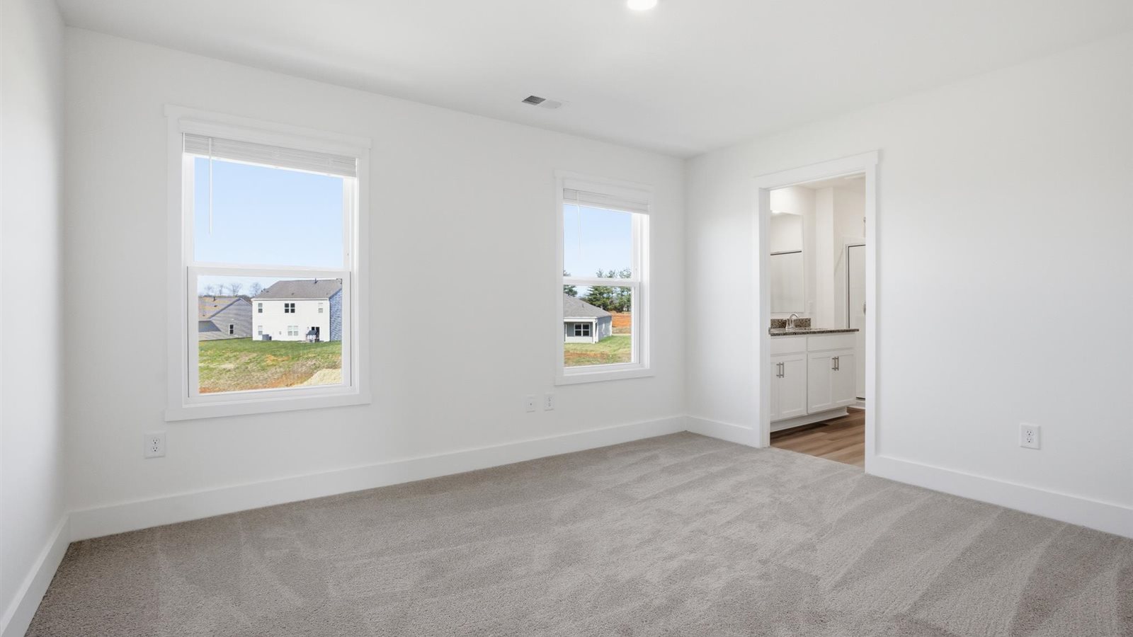 Primary bedroom with plush carpet floors and double light allowing windows