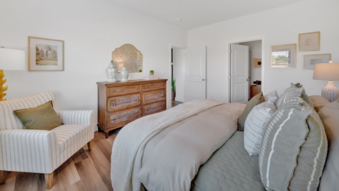 primary bedroom with a wall paper accent wall, white bed, and large window