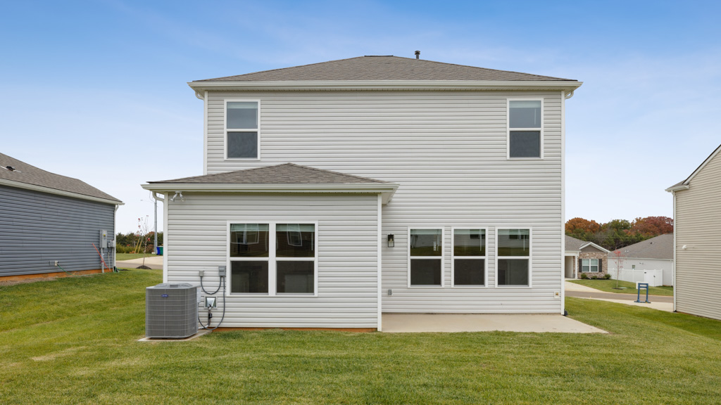 Back exterior of traditional two story home with vinyl, shake, and stone