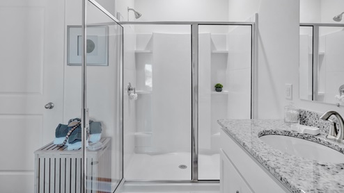 bathroom with dual vanity sinks, toilet, bath tub and a walk in shower