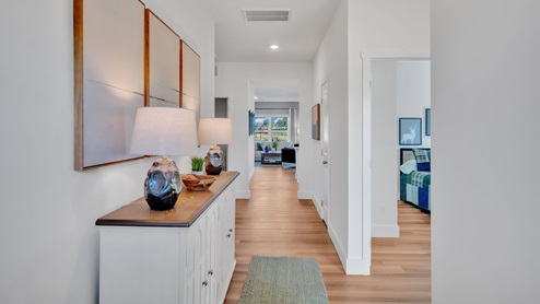 front entry hallway with brown flooring, white walls and a credenza with two lamps