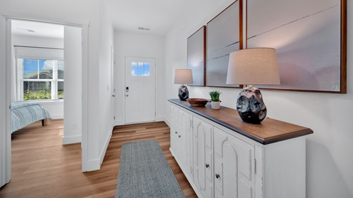front entry hallway with brown flooring, white walls and a credenza with two lamps