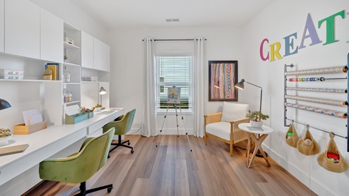 craft room with two white desks and green chairs and a window