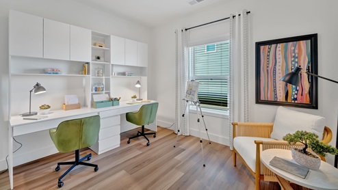 craft room with two white desks and green chairs and a window