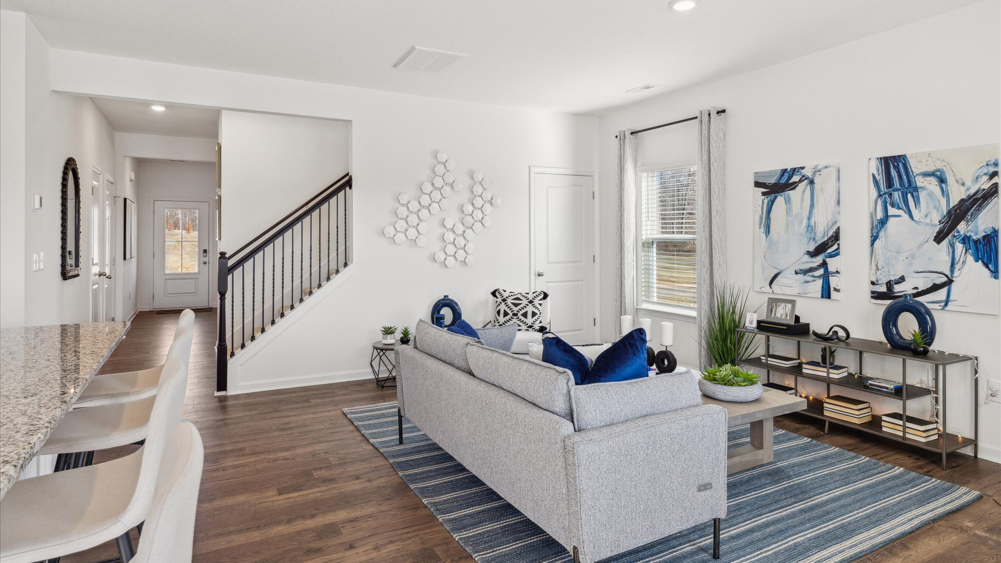 Living area with tile floors and stairs to second floor.