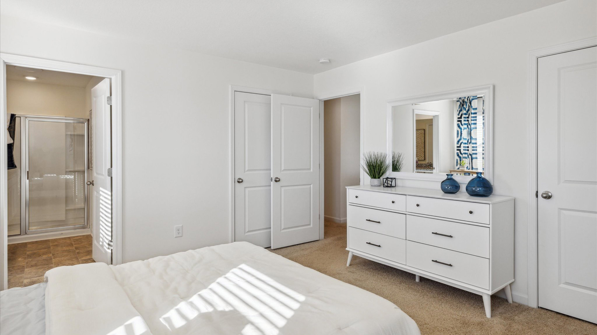A bedroom with carpeted floors and private bathroom.