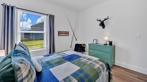 bedroom with blue bedding, a window and a green dresser