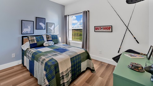 bedroom with blue bedding, a window and a green dresser