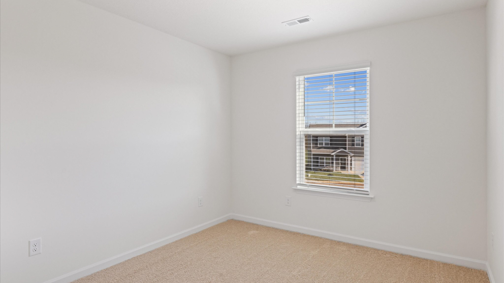 spacious bedroom with white walls and light brown carpet
