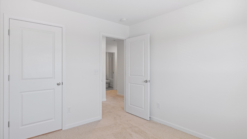 spacious bedroom with white walls and light brown carpet
