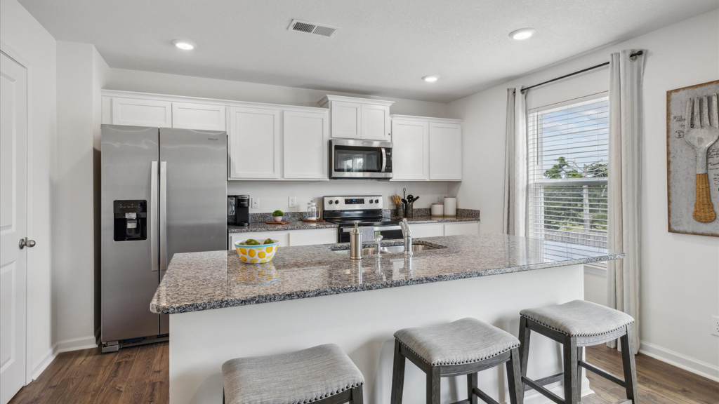 Kitchen with quartz counterops, stainless steel appliances, and shaker style cabinets