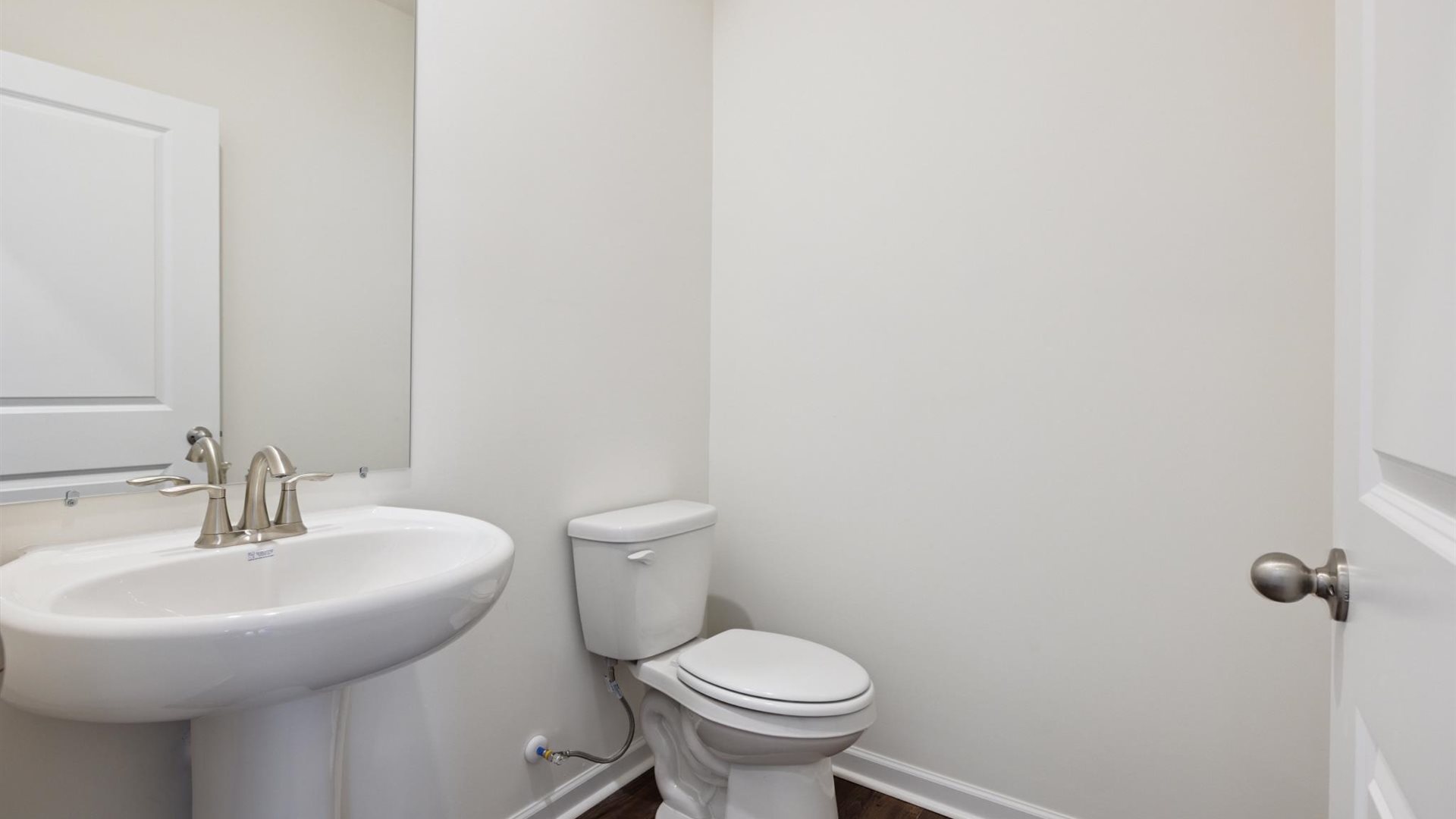 Half bath with door opening to hallway, pedestal sink, mirror visible with shiny faucet in Cherokee Crossing