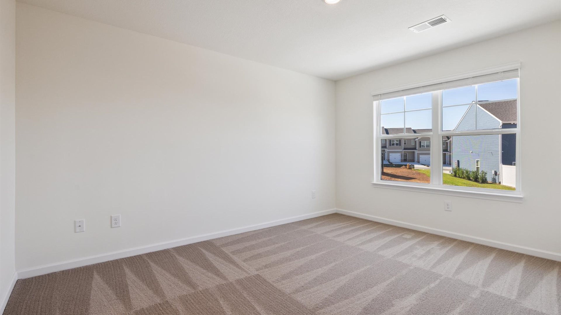 Primary bedroom in this townhome features double windows, soft carpet, walk-in closet, and a private spa-inspired ensuite bath