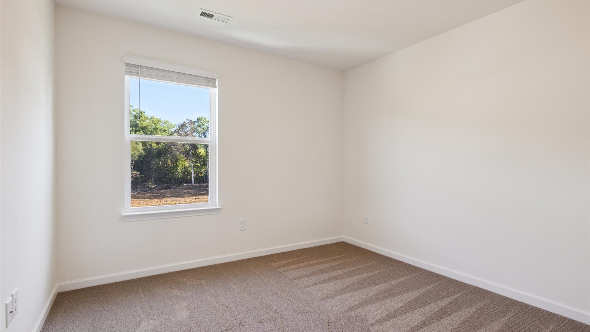 Primary bedroom in this townhome features ample space, double windows, soft carpet, walk-in closet, and a private ensuite bath