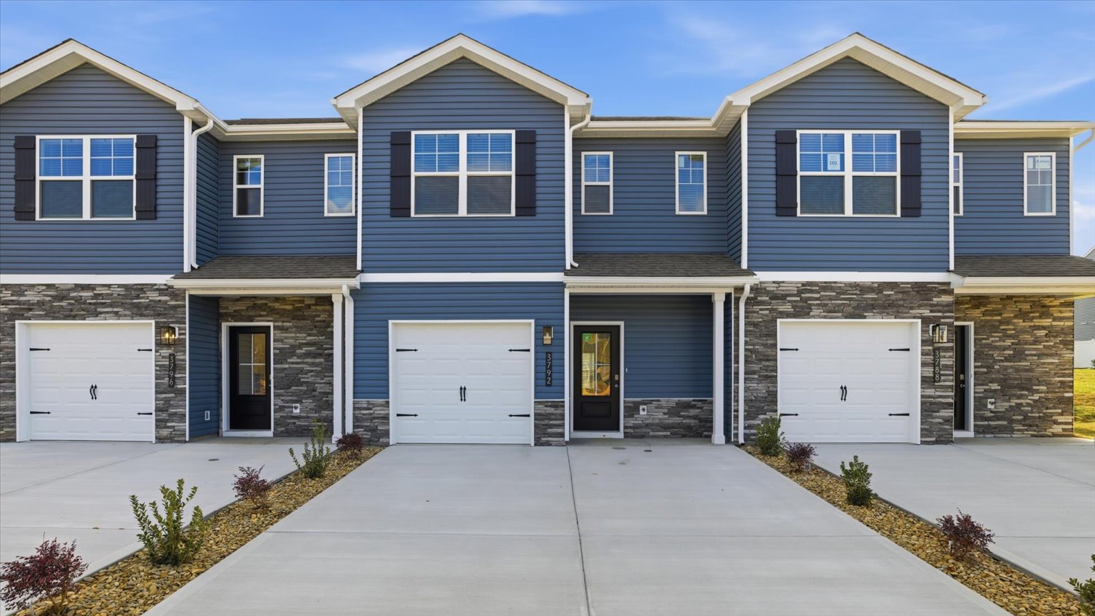 Front exterior of traditional two story townhome with vinyl, board and batten, and brick