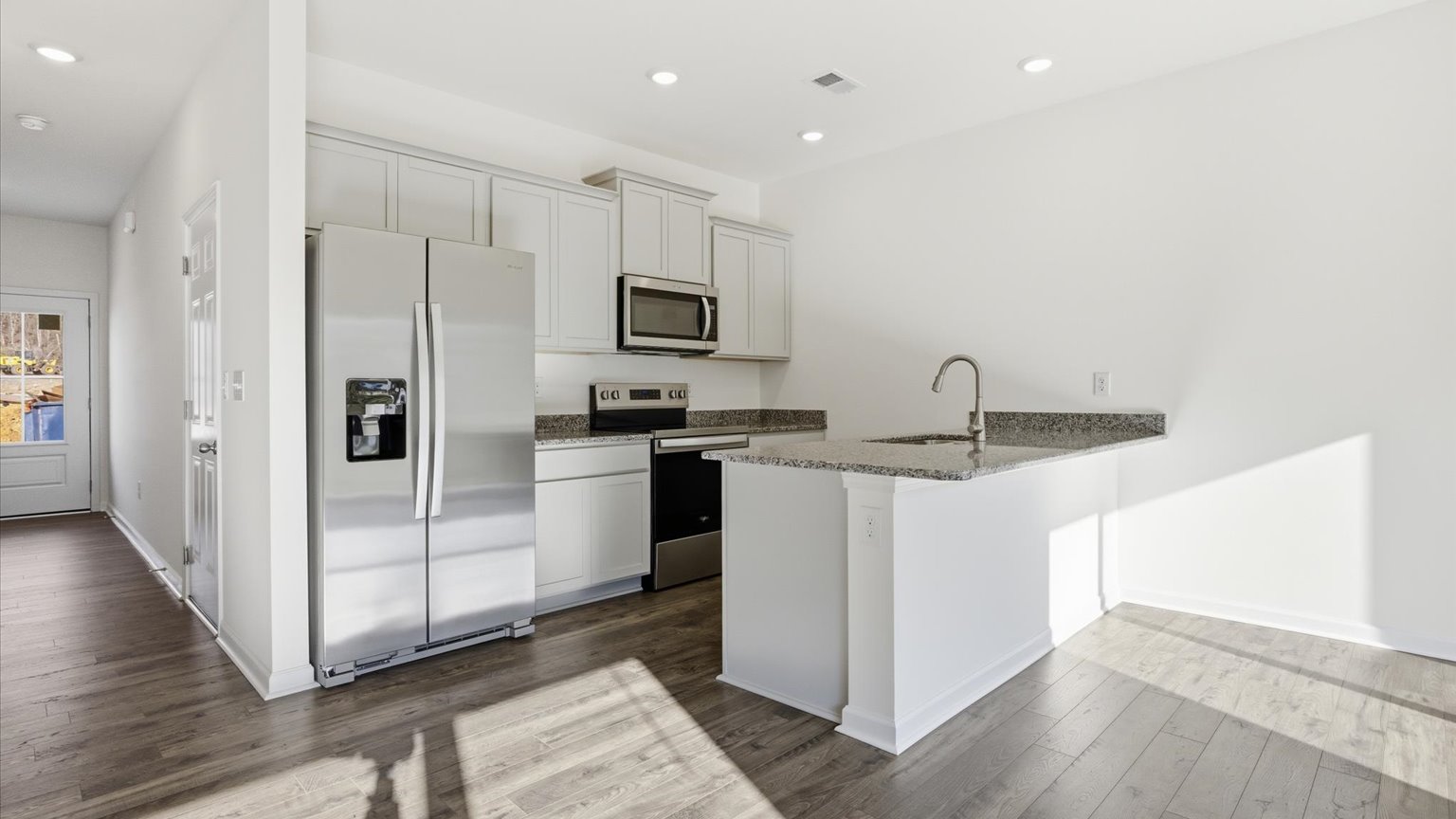 Kitchen with quartz counterops, stainless steel appliances, and shaker style cabinets