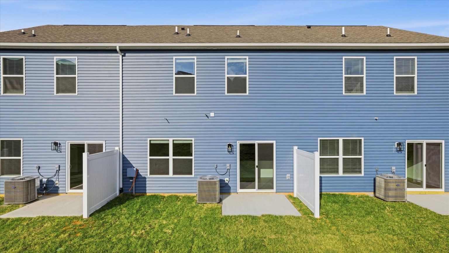 Back exterior of traditional two story townhome with vinyl, board and batten, and brick