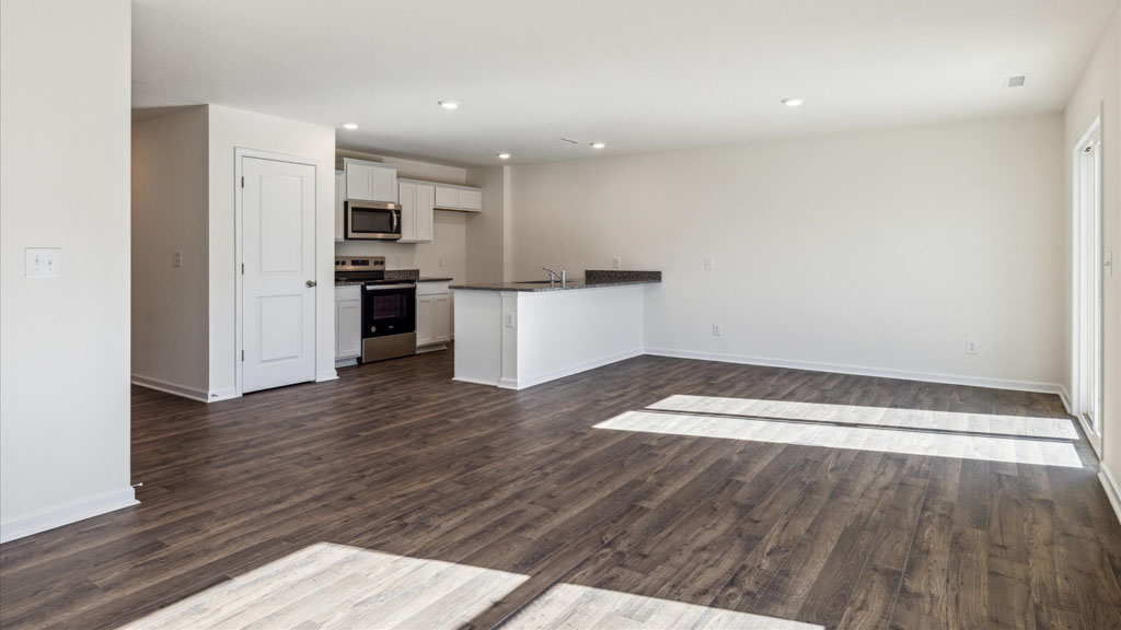 Living room looking to kitchen, dining, outdoor areas in this new home features natural light, with fresh open concept flow