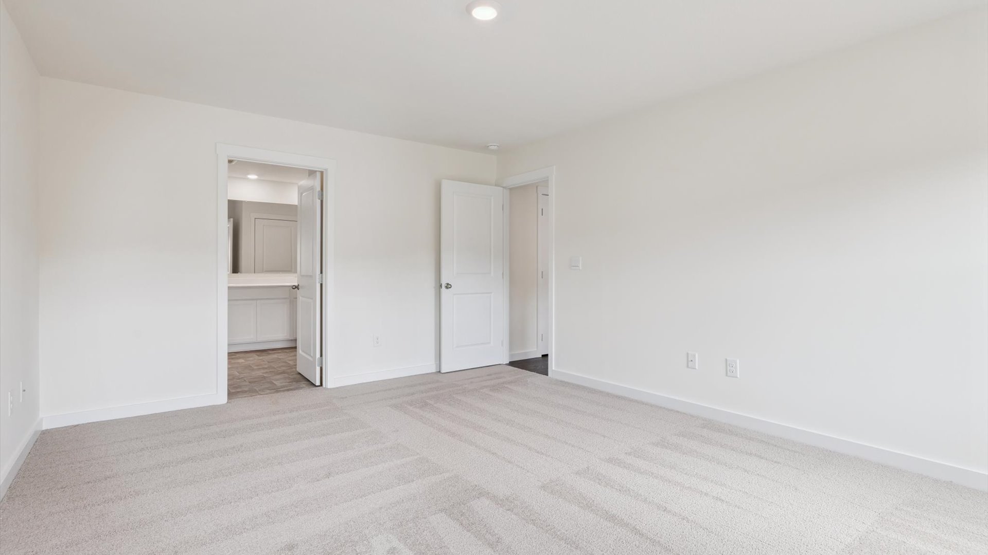 Primary bedroom features ample space, double windows, soft carpet, a stylish walk-in closet, and a private ensuite bath