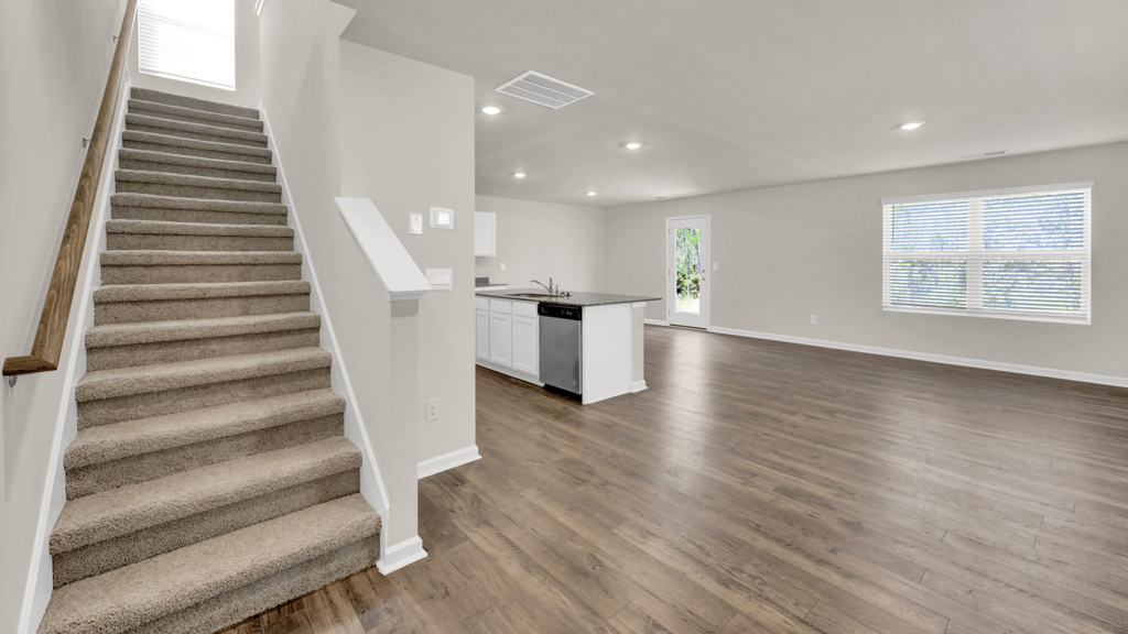 Spacious living room with view into dining and kitchen areas, and upstairs access at Price's Point