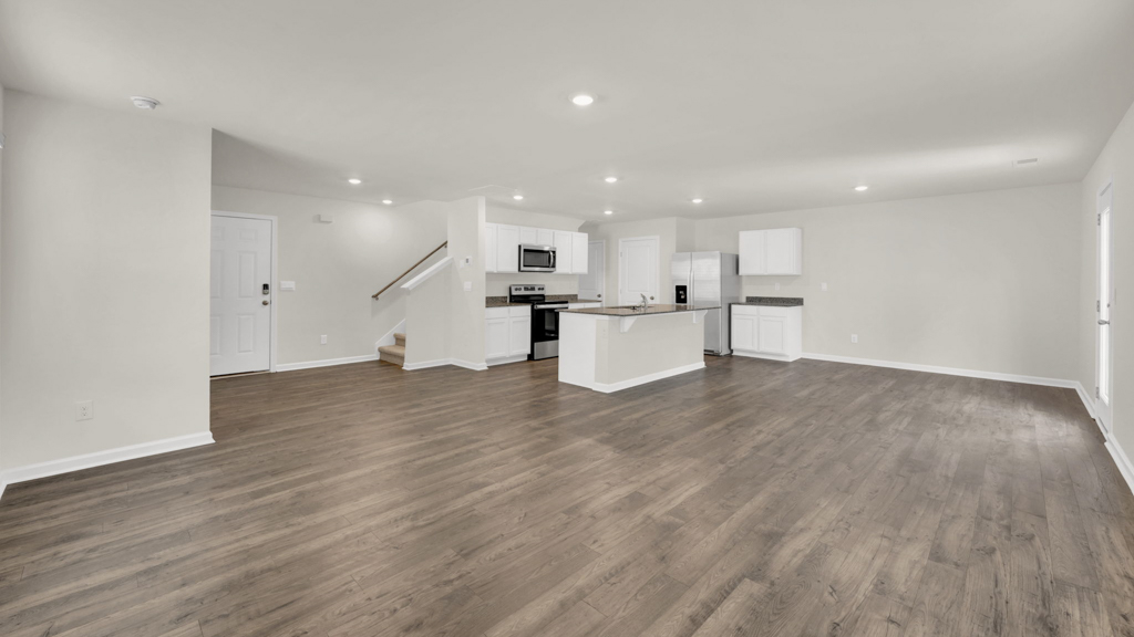 Spacious living room with view into backyard, connecting dining and kitchen areas at Price's Point