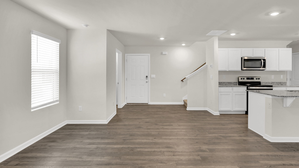 Living room looking to kitchen, dining, outdoor areas in this new home features natural light, with fresh open concept flow