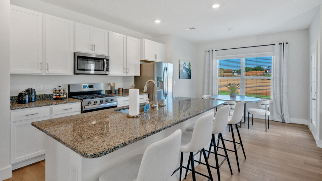 Central kitchen island anchors the home adding a dining option, full sink, pantry and storage, multi-prep zones