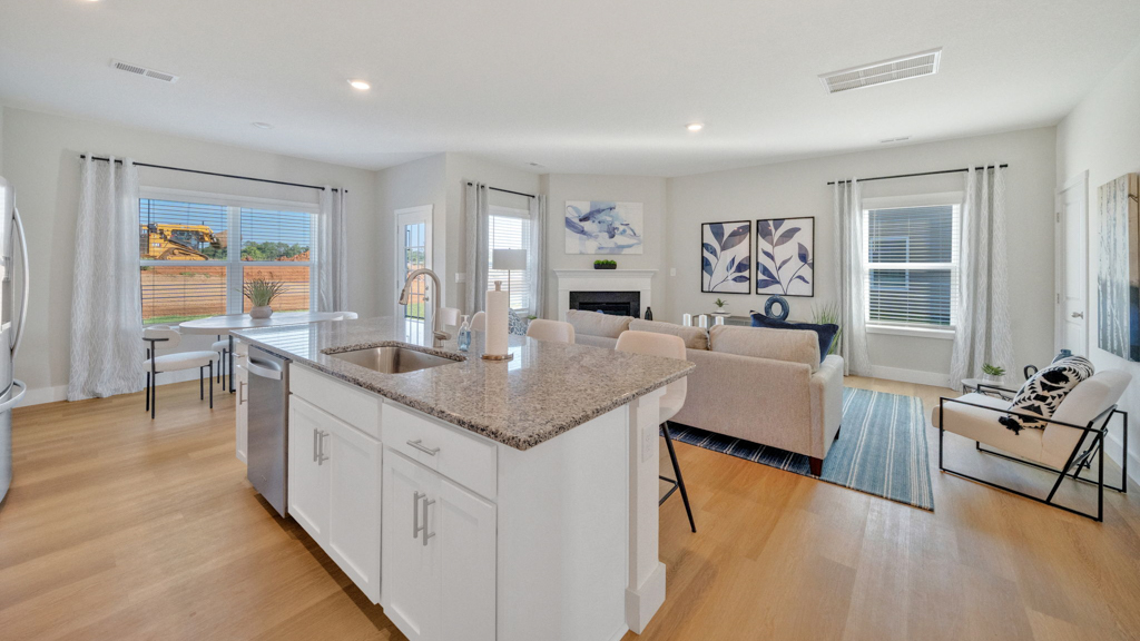 Living room looking to dining and kitchen areas in this new home features natural light, with fresh open concept flow