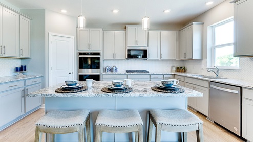 The grant kitchen shown with double ovens, stainless appliances.