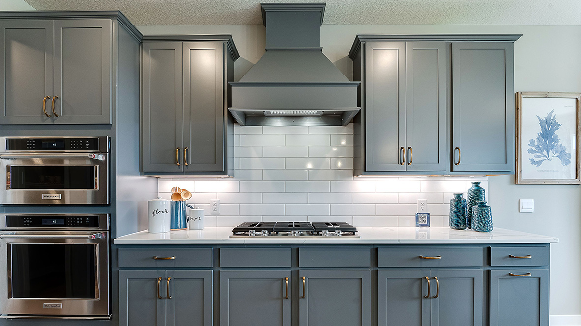 Straight on view of kitchen cabinets and backsplash with stainless steel appliances