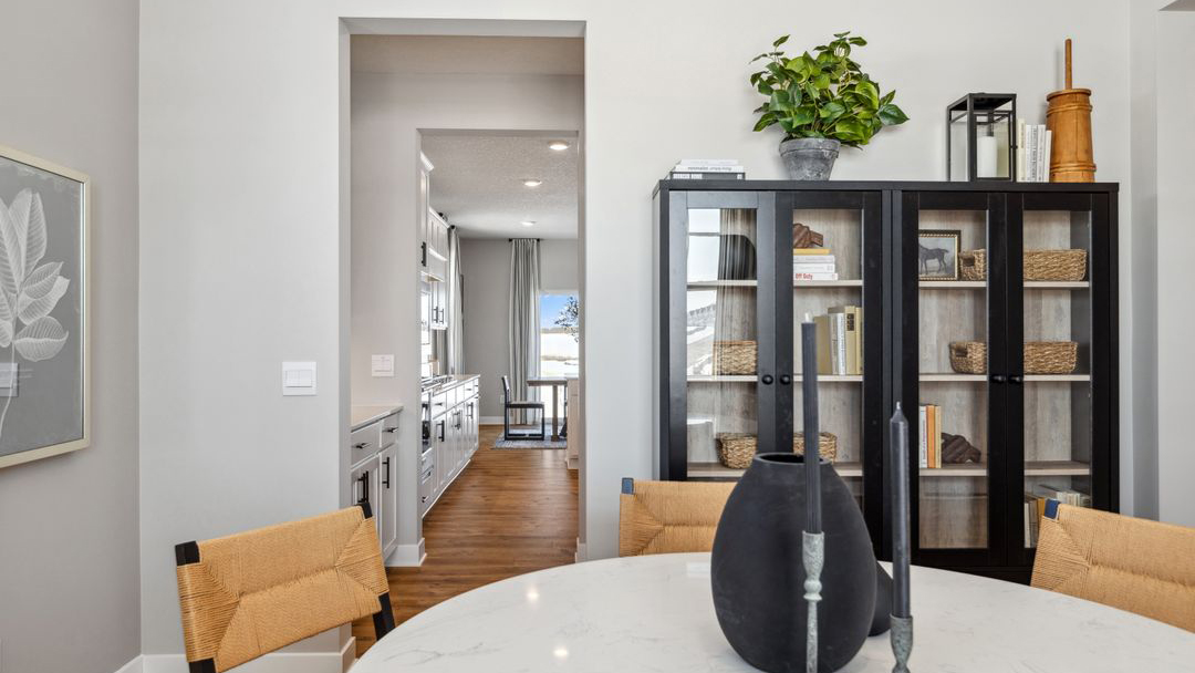 Formal dining room featuring a white table and chairs, set on laminate wood flooring, with a butler's pantry in the background.