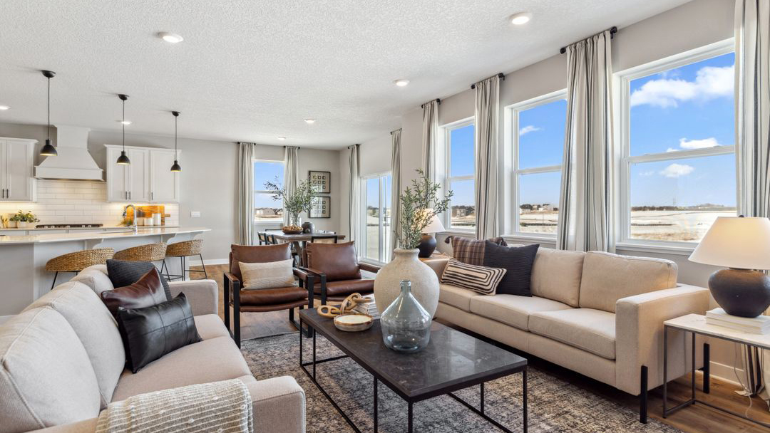 Open concept living room, kitchen, and dining area in a modern new construction home, featuring bright, airy spaces.
