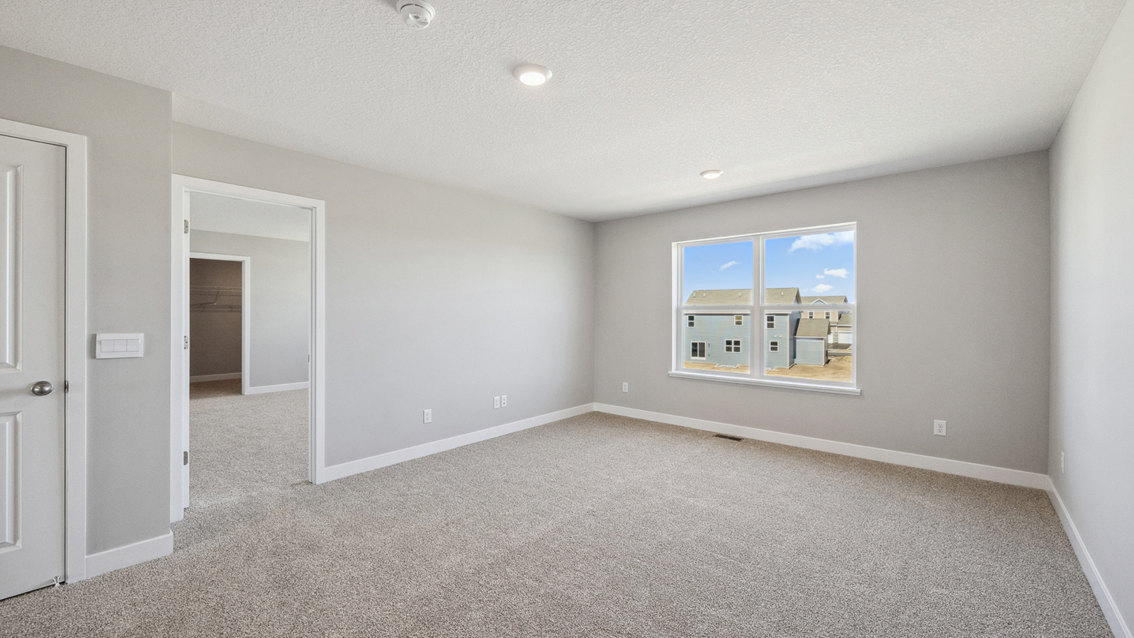 unfurnished loft room with beige carpet, light grey walls and a window