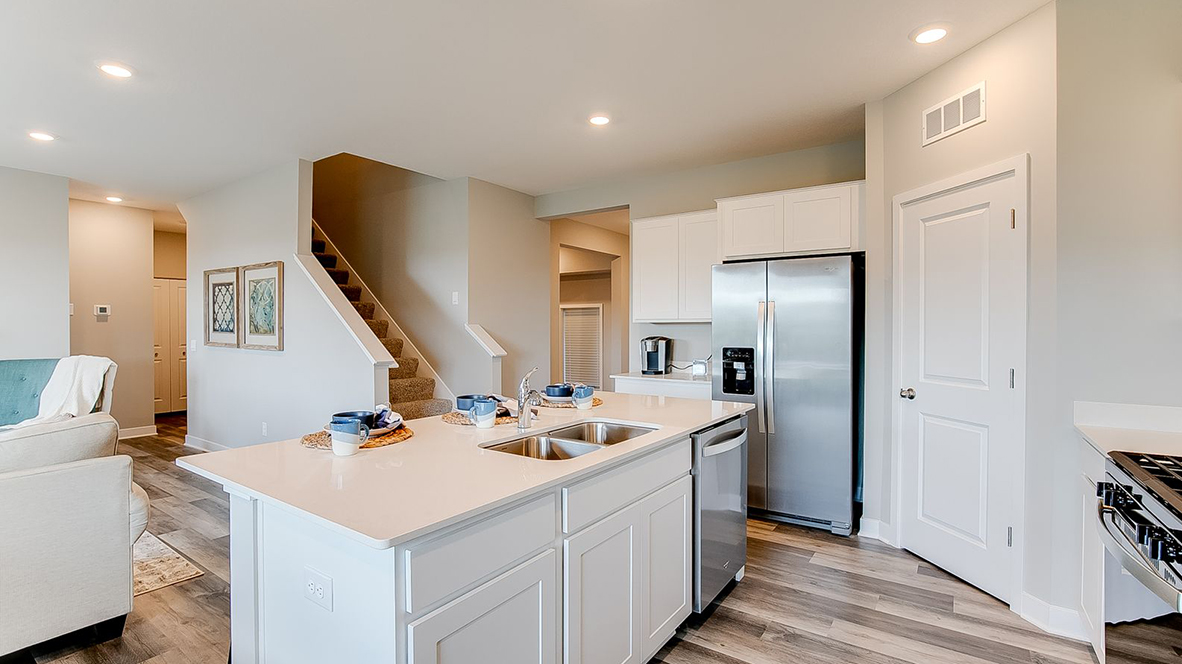 Angled view of kitchen with white cabinets and stainless steel appliances.