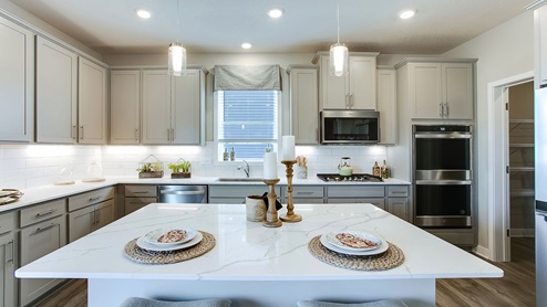 Jordan signature kitchen with gray cabinets, double ovens and a gas cooktop.