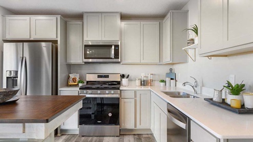 Open kitchen with stainless appliances and quartz countertops.