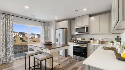 Open kitchen with stainless appliances and quartz countertops.