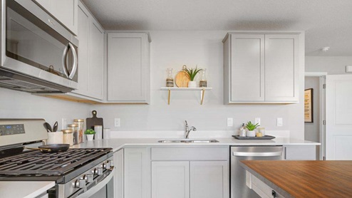 Open kitchen with stainless appliances and quartz countertops.