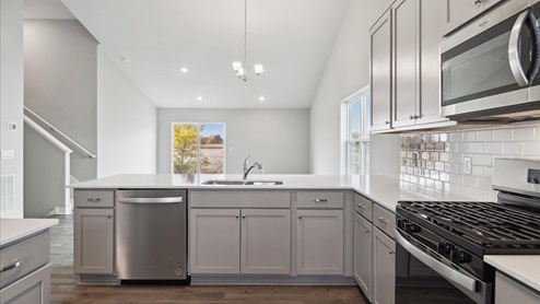 The kitchen features quartz countertops, tiled backsplash and stainless appliances.
