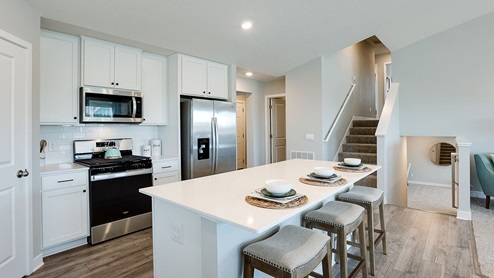 The kitchen has stainless appliances, tiled kitchen backsplash and quartz countertops.