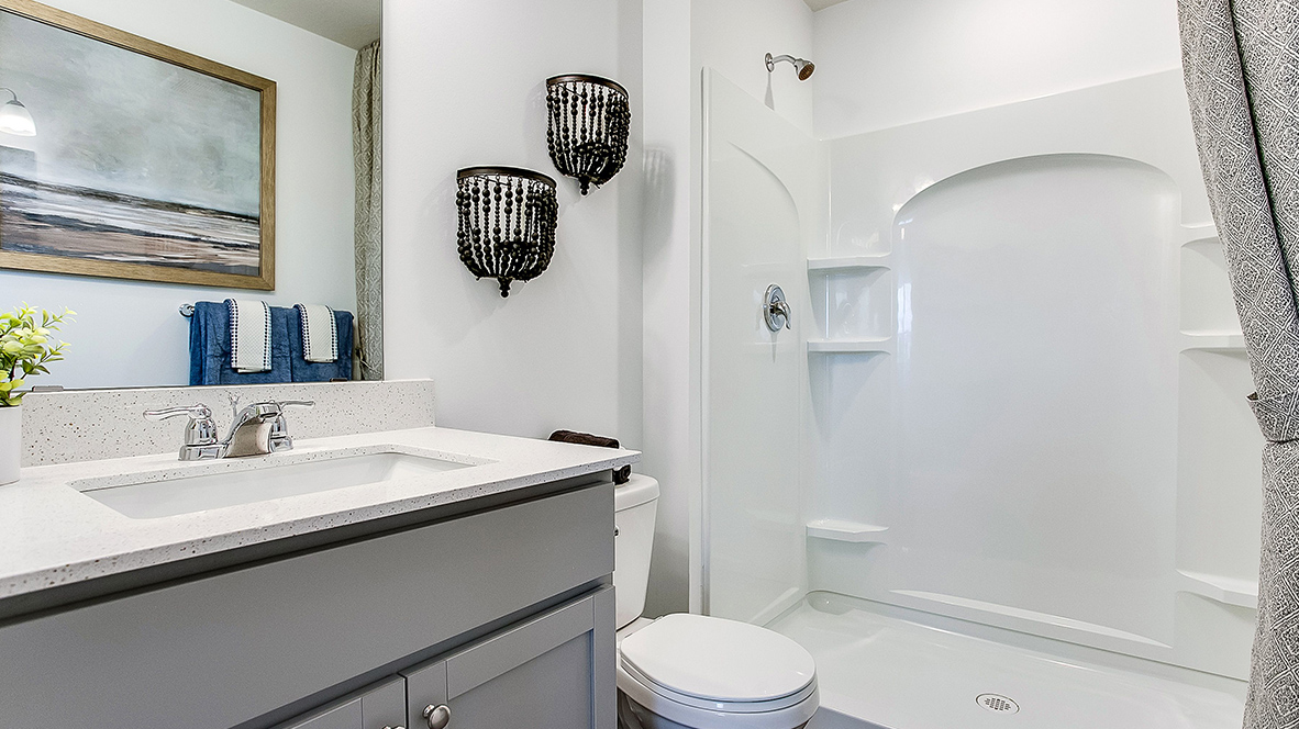 Secondary bathroom with willow gray cabinets and quartz vanity countertop.