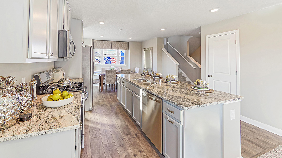 Angled view of kitchen island with gray cabinetry and granite countertops.