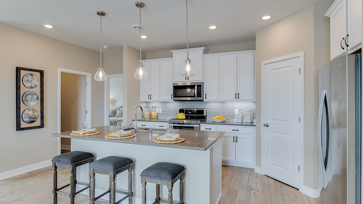 Angled view of kitchen with stainless steel appliances and four-person island.