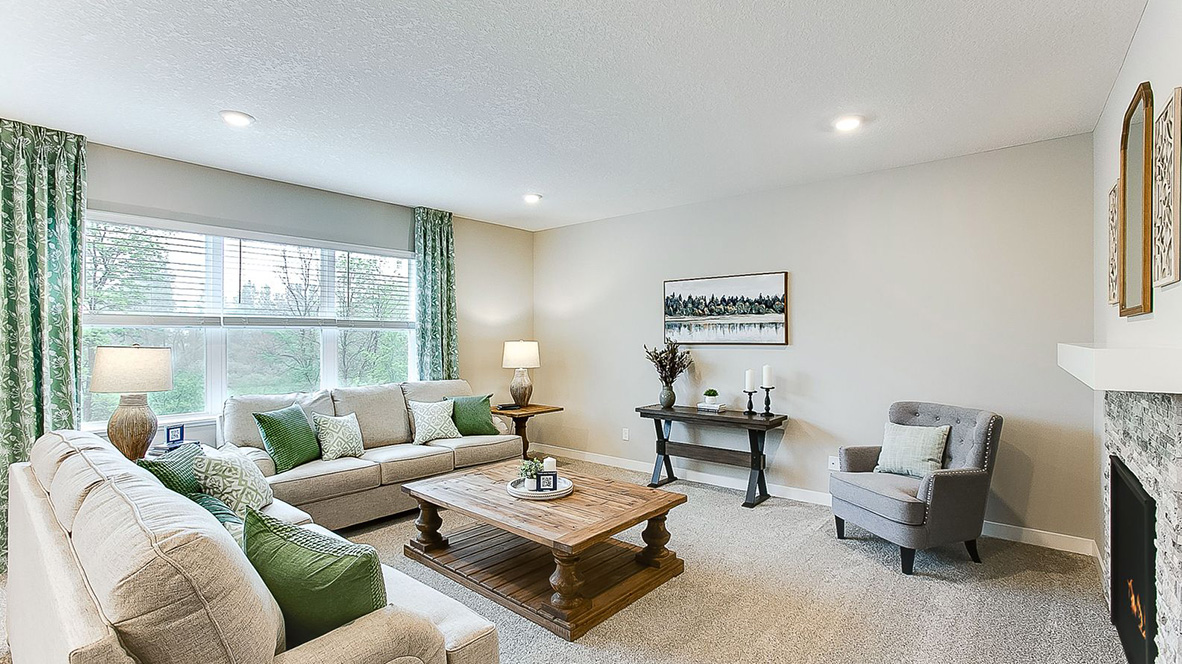 Carpeted living room with two-sided gas fireplace and stone surround.