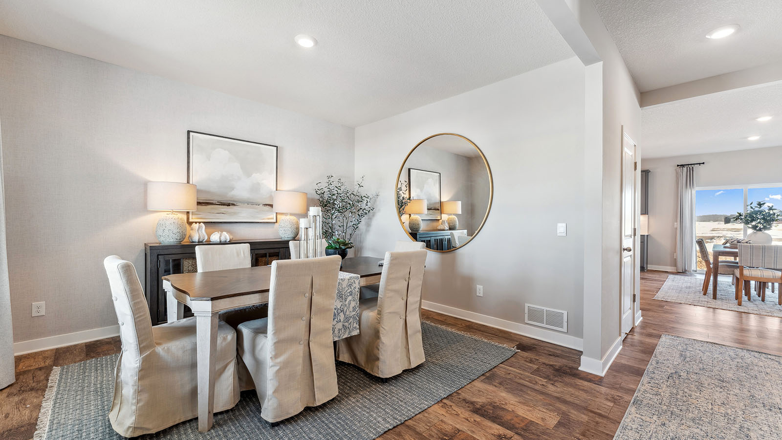 A bright, formal dining room adjacent to a sleek kitchen in a new construction home