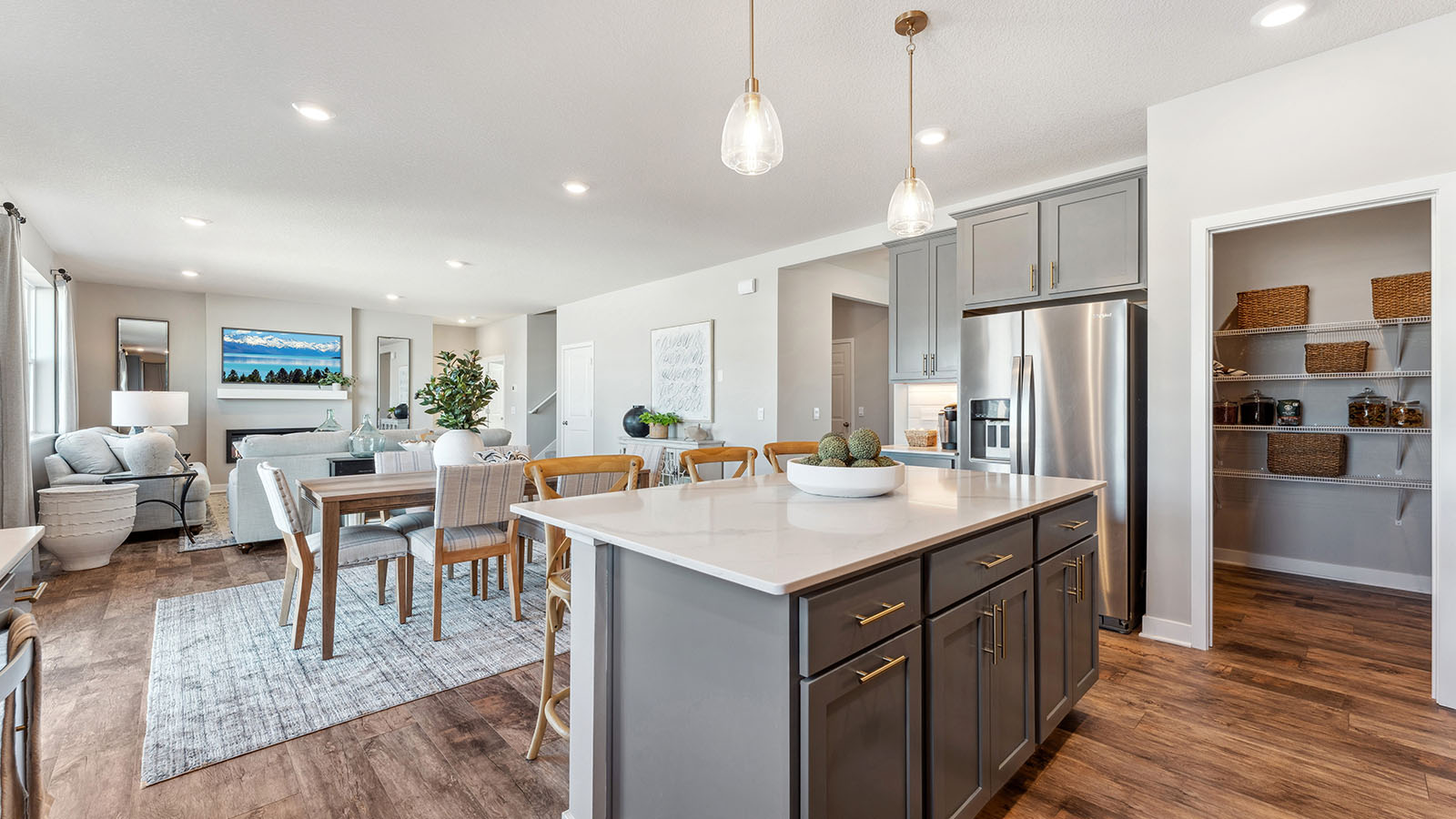 Open-concept kitchen, dinette, and living room showcasing beautiful laminate wood floors and contemporary decor
