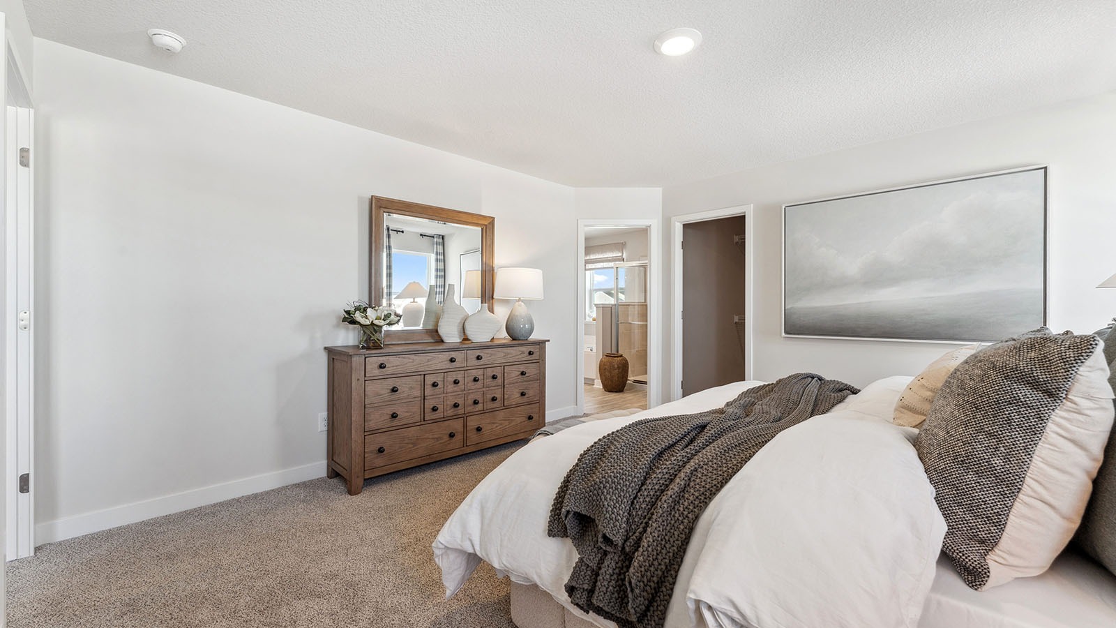Carpeted bedroom suite with natural lighting, spacious walk in closet and private bathroom