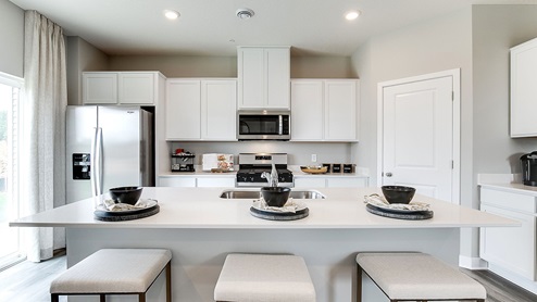Straight on view of kitchen with white cabinetry and stainless steel appliances.